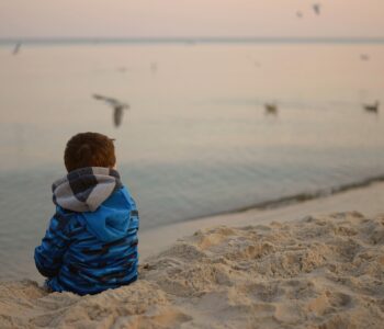 boy sitting alone looking out at the sea.