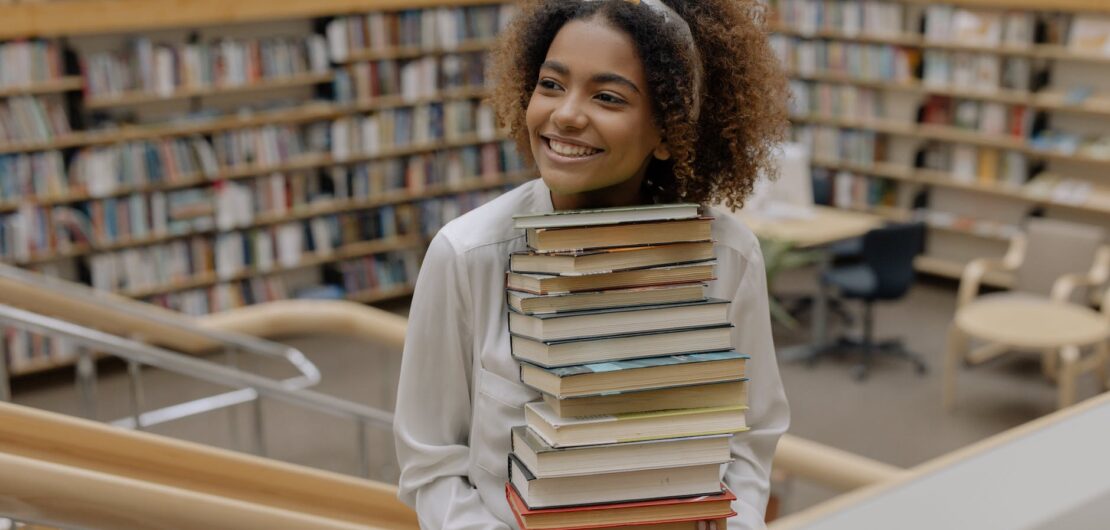 photo of woman carrying stack of books