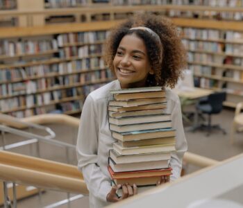 photo of woman carrying stack of books