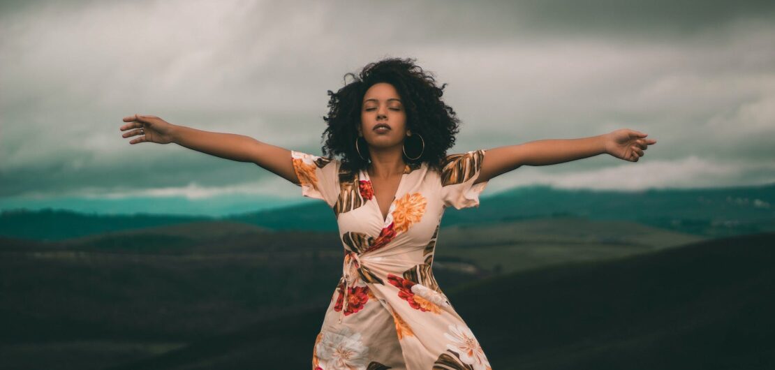 woman in white and red floral dress standing on green grass field