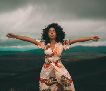 woman in white and red floral dress standing on green grass field