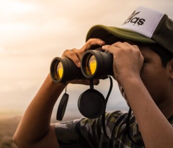 man looking in binoculars during sunset