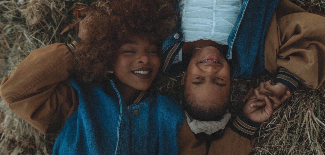 picture of mother and daughter lying on back close together smiling.