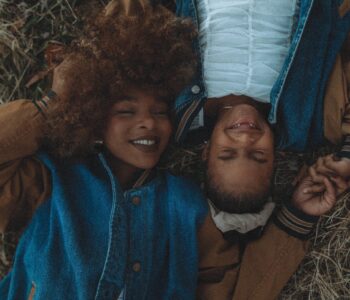 picture of mother and daughter lying on back close together smiling.
