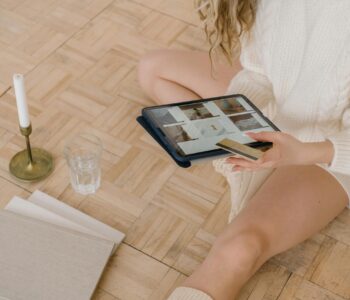 Woman using a tablet for online shopping while sitting indoors with a bank card.